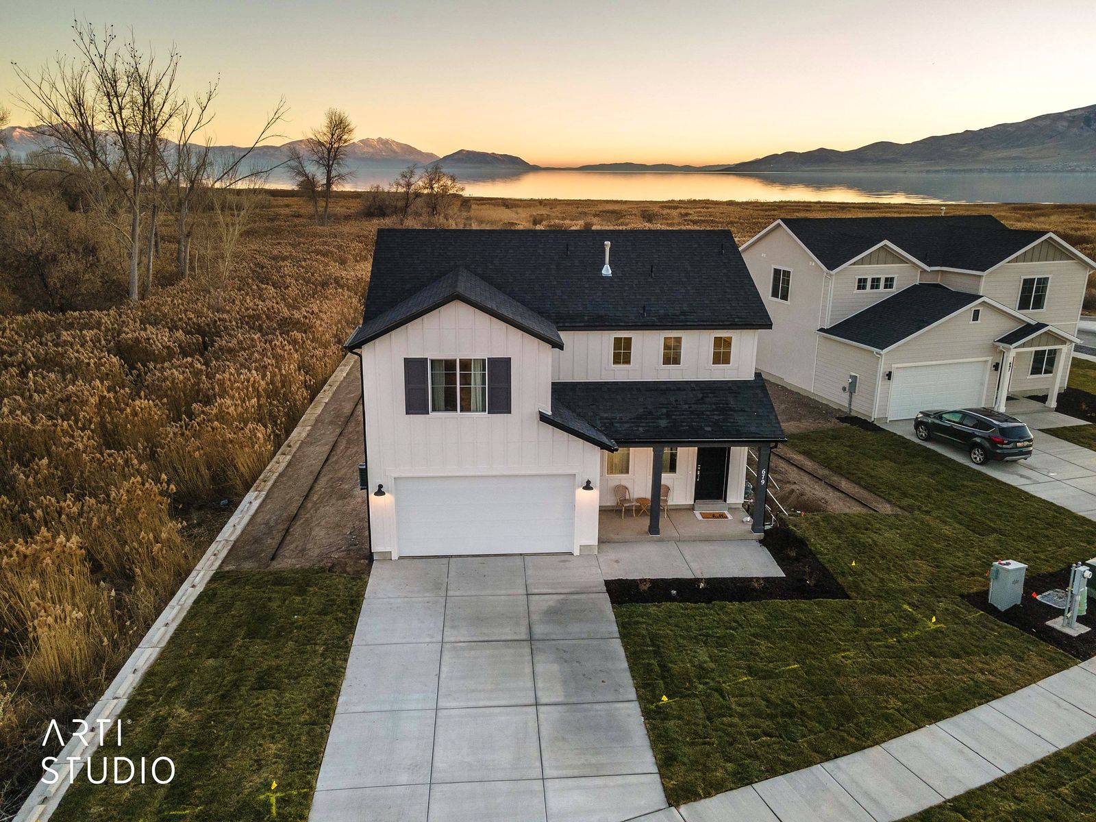 Aerial view of the white two-story home at dusk with Utah Lake and the mountains beyond