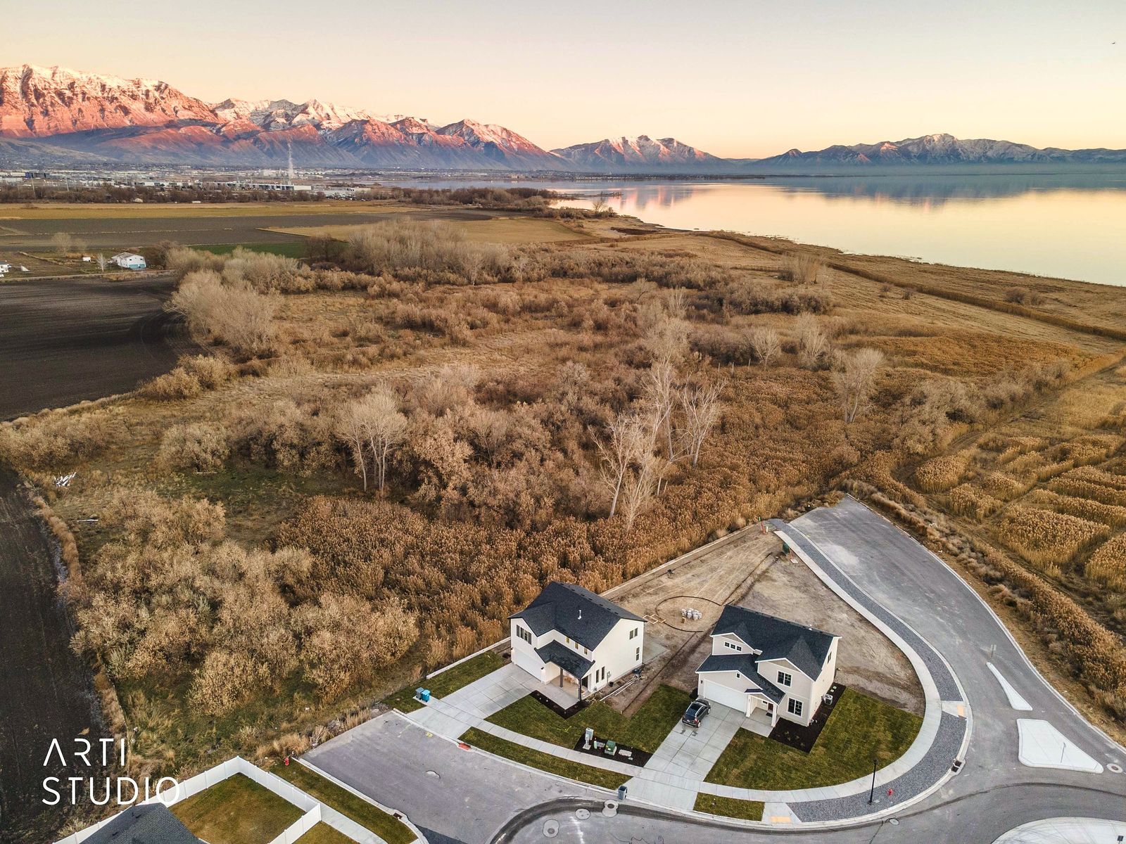 Aerial view toward the Wasatch mountains at sunset over the neighborhood and wetlands