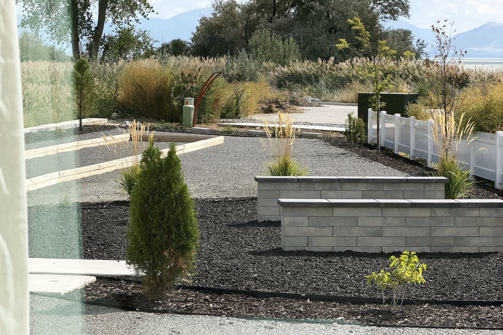 Xeriscaped backyard with stone planters, evergreens and gravel beds