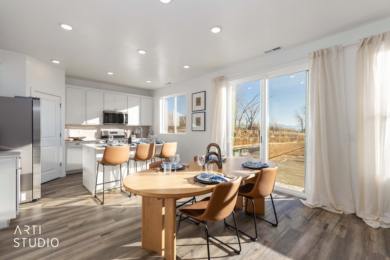 Round oak dining table and leather chairs beside windows with a lake view