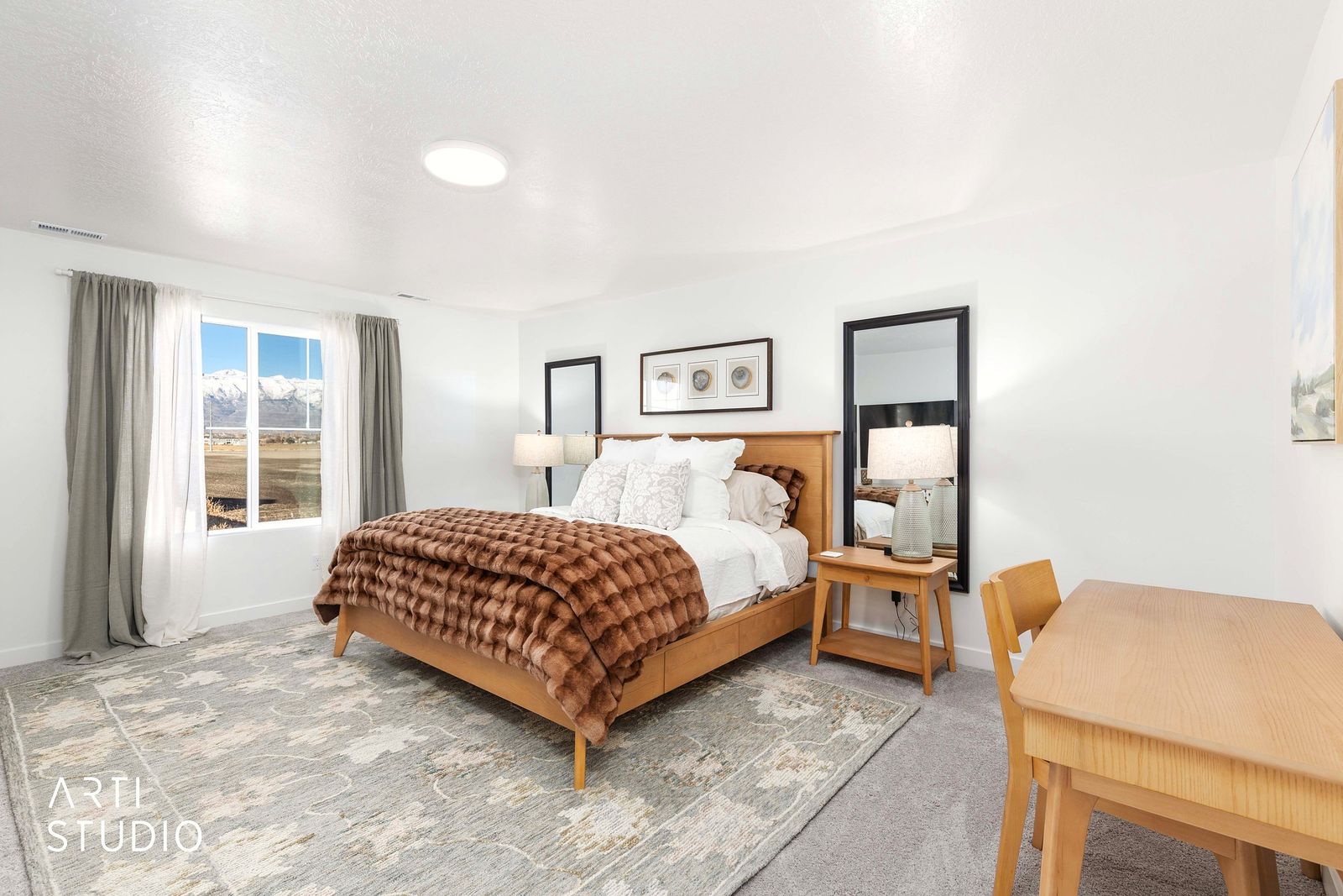 Primary bedroom with a cognac throw, wood furniture and a large window