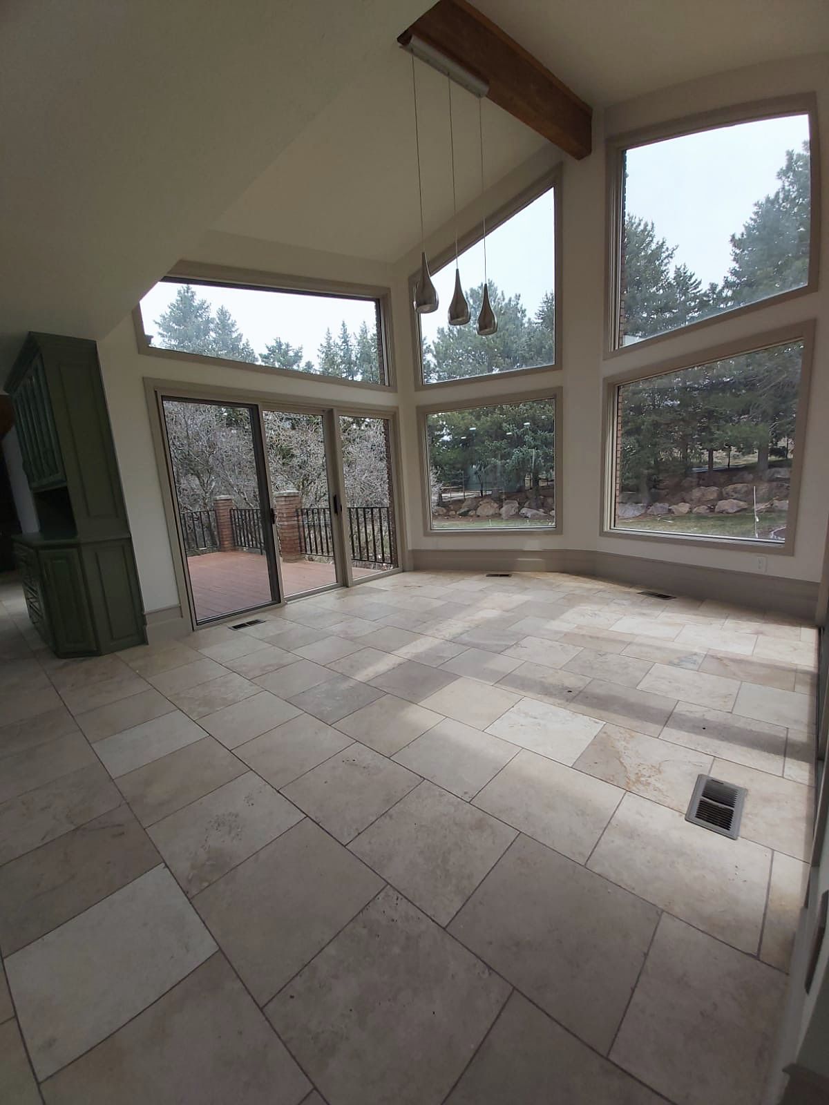 Great room with angled floor-to-ceiling windows and stone tile floors