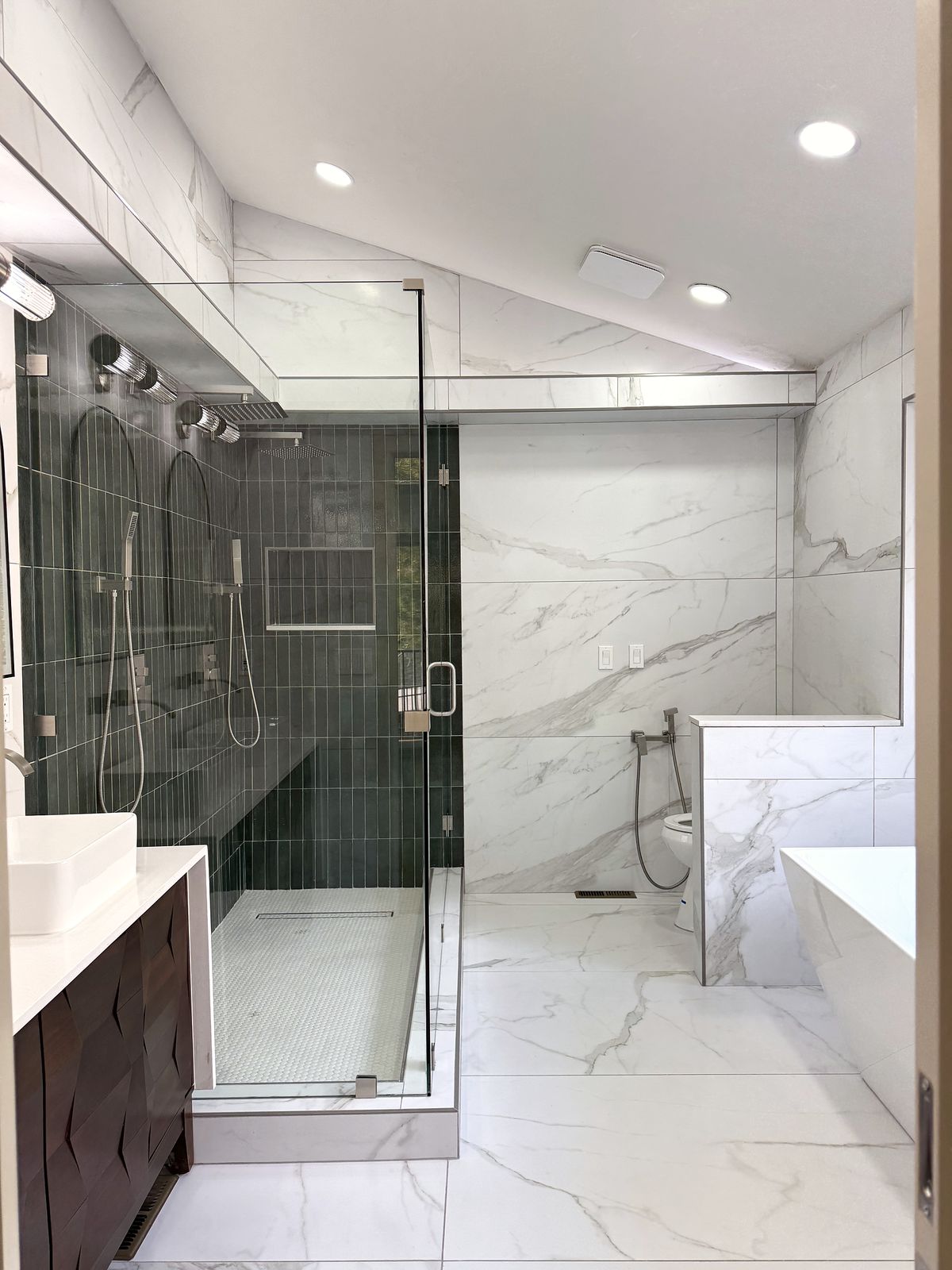 Primary bath with marble-look tile, a glass shower with deep green tile and a freestanding tub