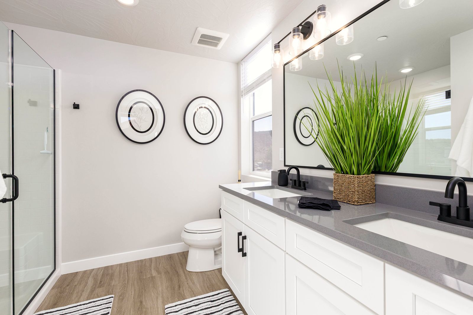 Bathroom with a double vanity, round wall accents and a potted grass