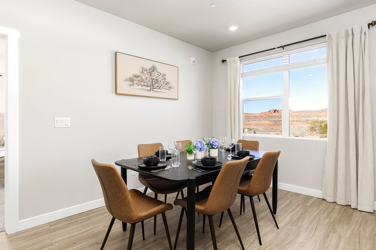 Dining table with leather chairs, a botanical print and a window to the desert