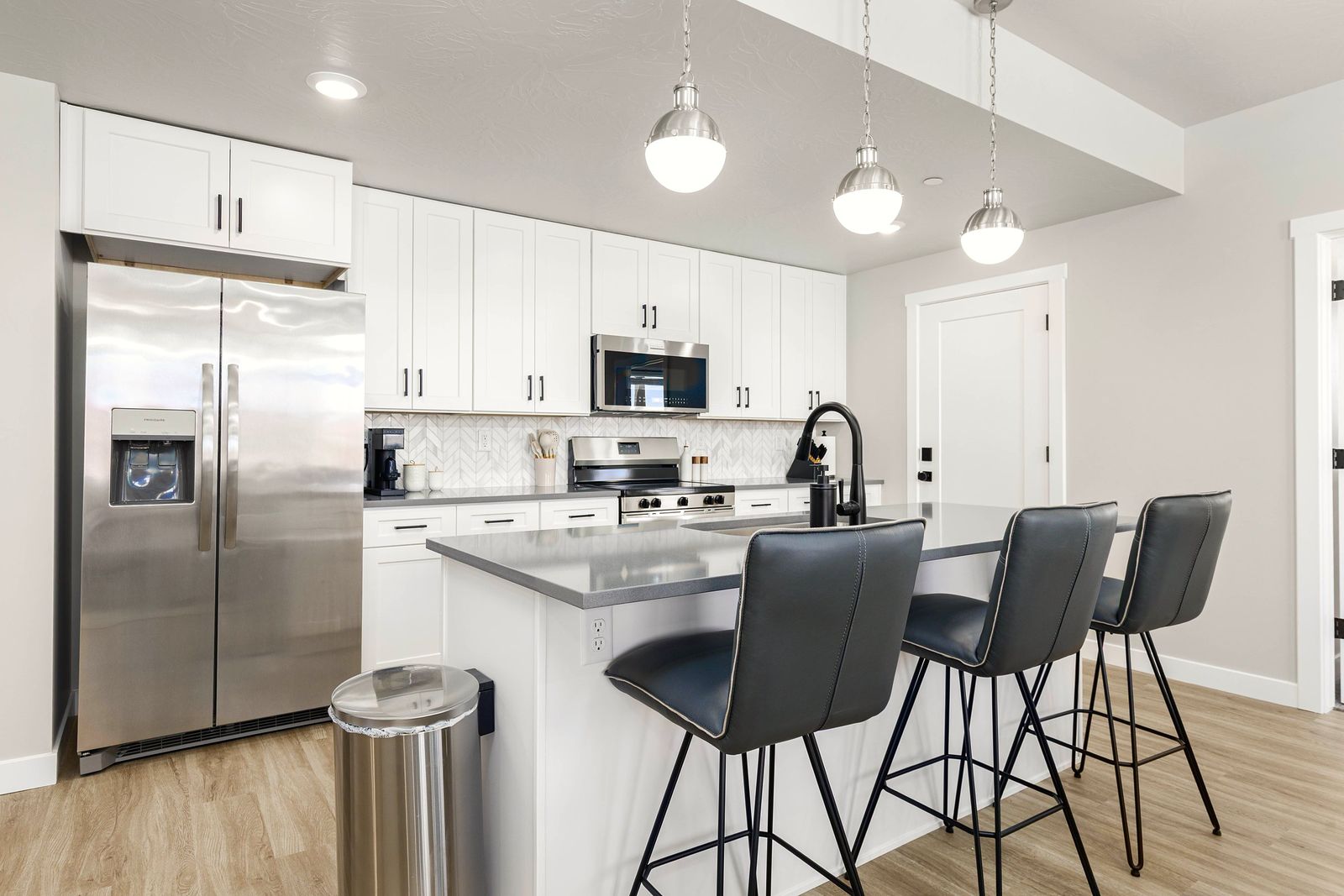 White kitchen with dark counter stools and pendant lights
