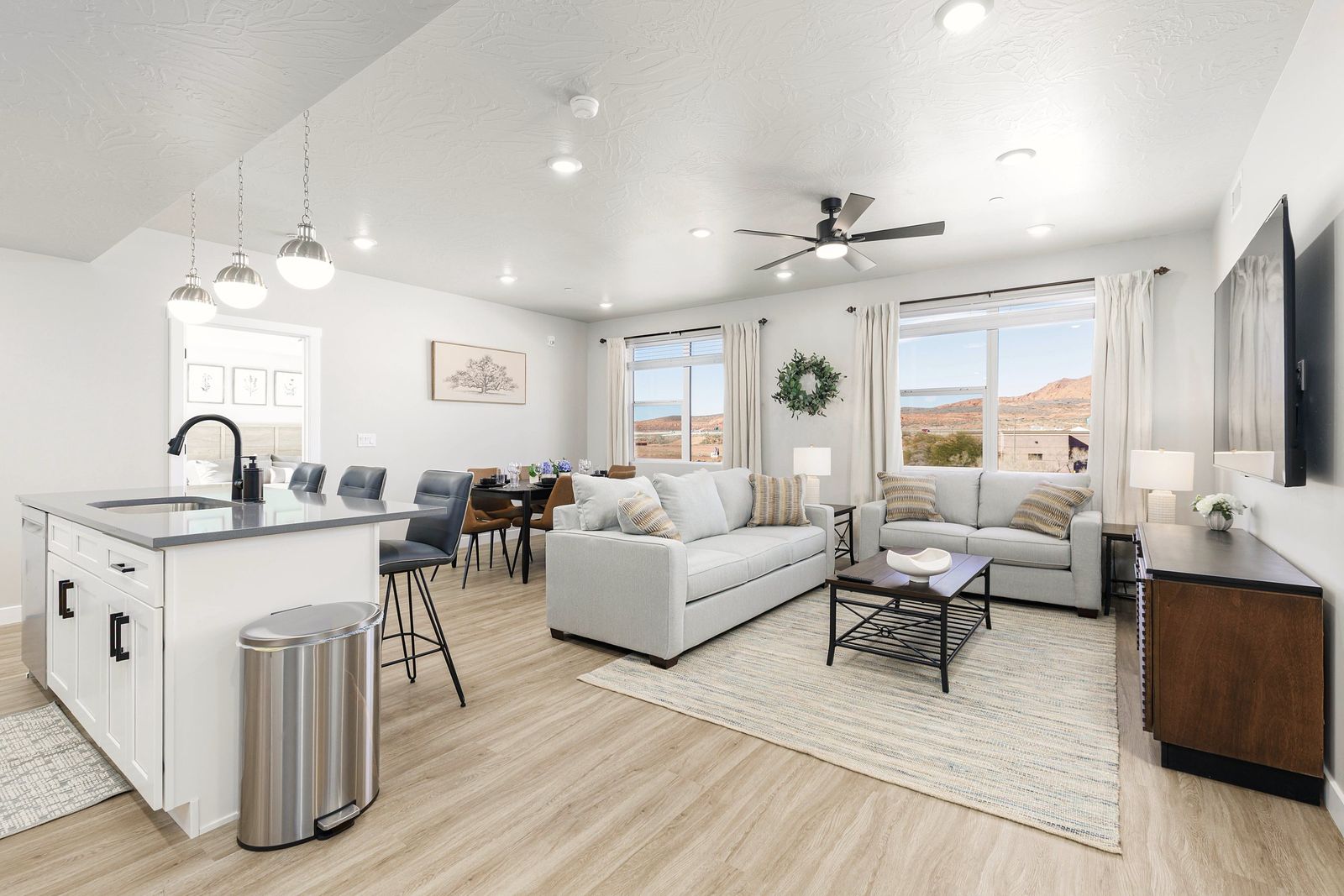 Open-plan living, dining and kitchen with light floors and desert views