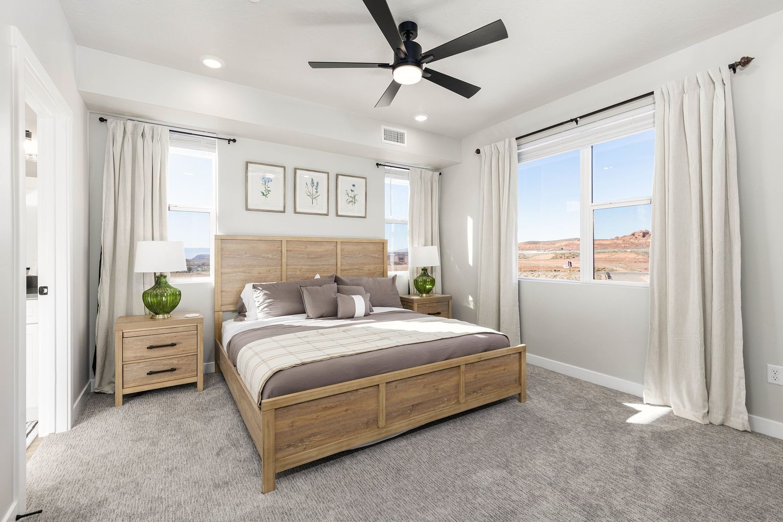 Primary bedroom with a light wood bed, neutral bedding and botanical prints