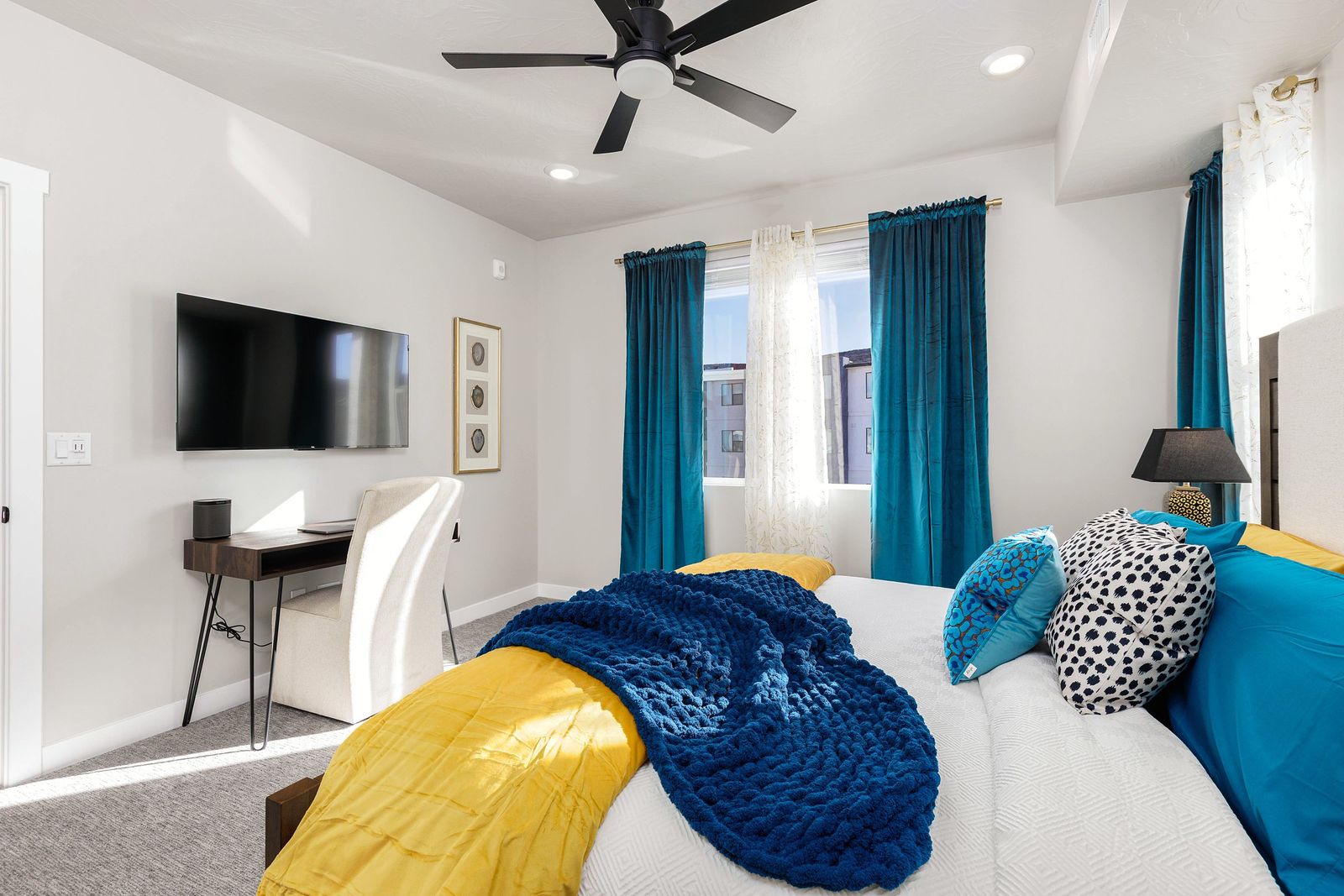 Bed detail with navy knit throw, yellow blanket and patterned pillows