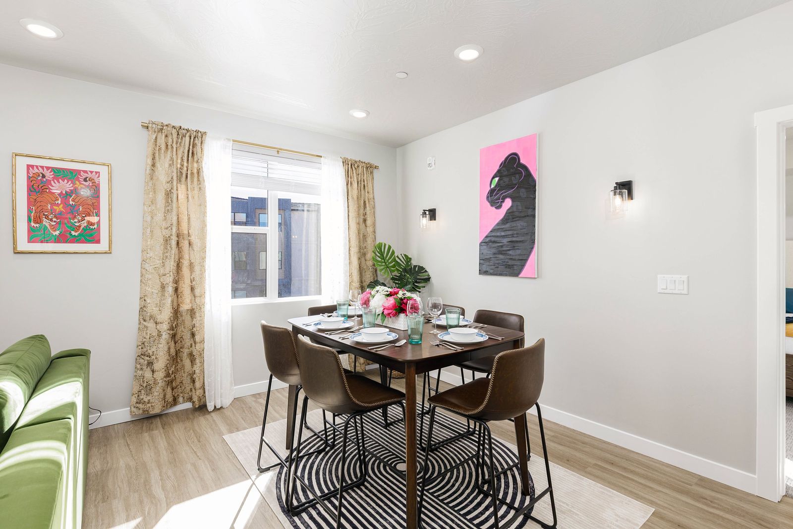 Dining nook with a set table, pink panther artwork and patterned drapery