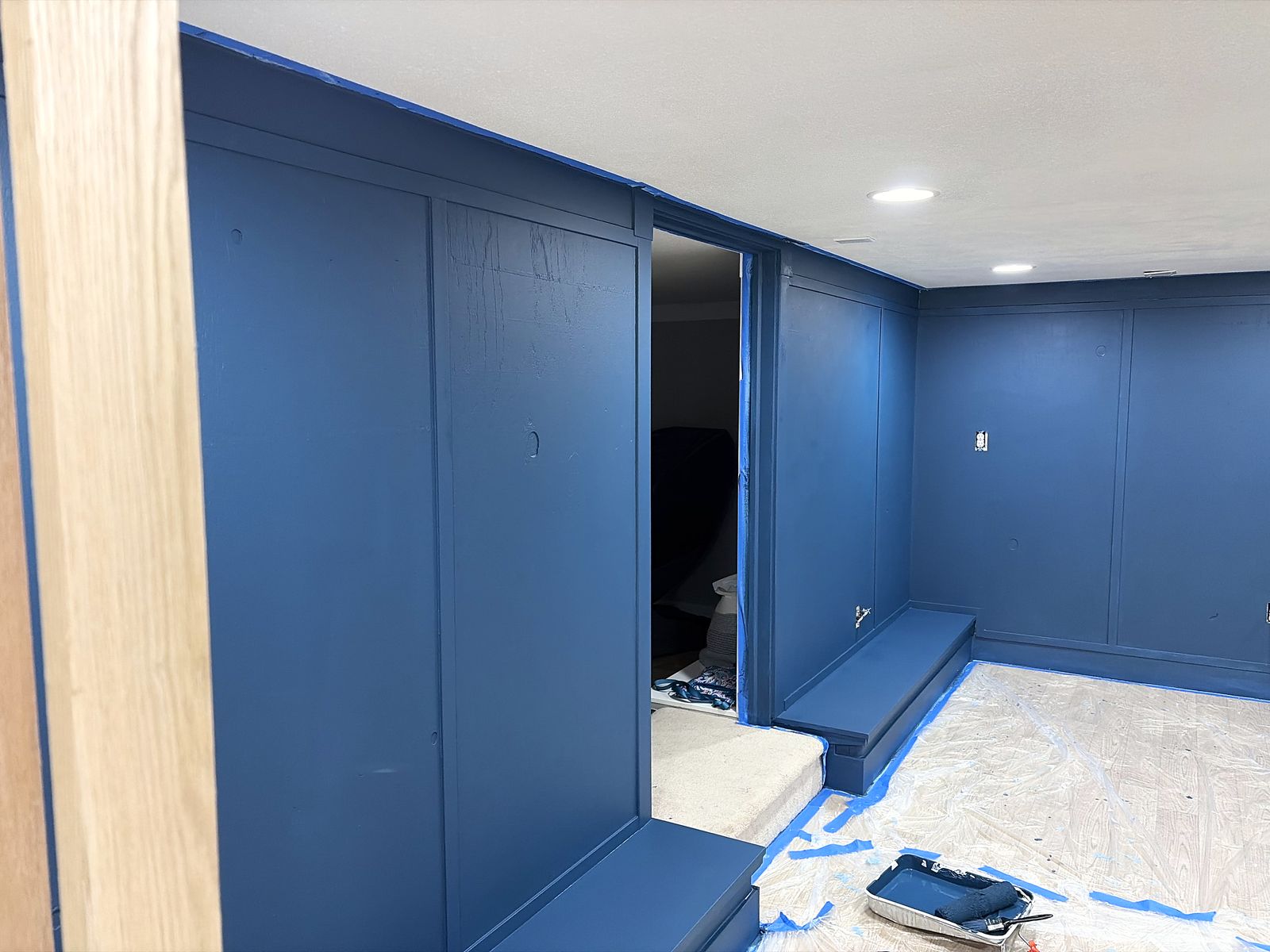 Blue-painted built-in benches beside the stair and a wood slat divider, during the renovation