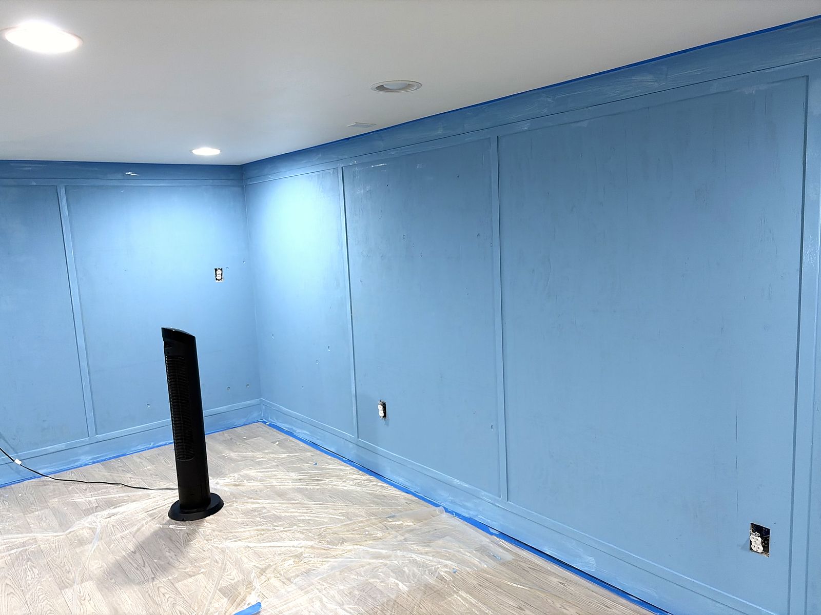 Basement with new paneling painted deep blue, floors still covered
