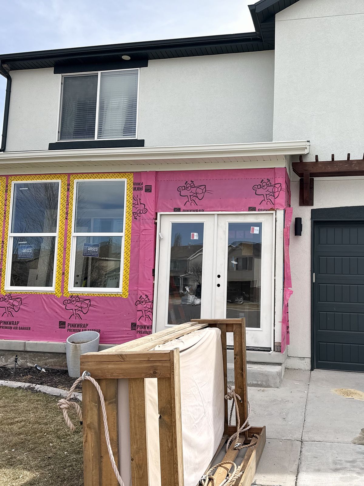 Front of the house with the porch newly framed in, new windows and French doors, wrapped for weather