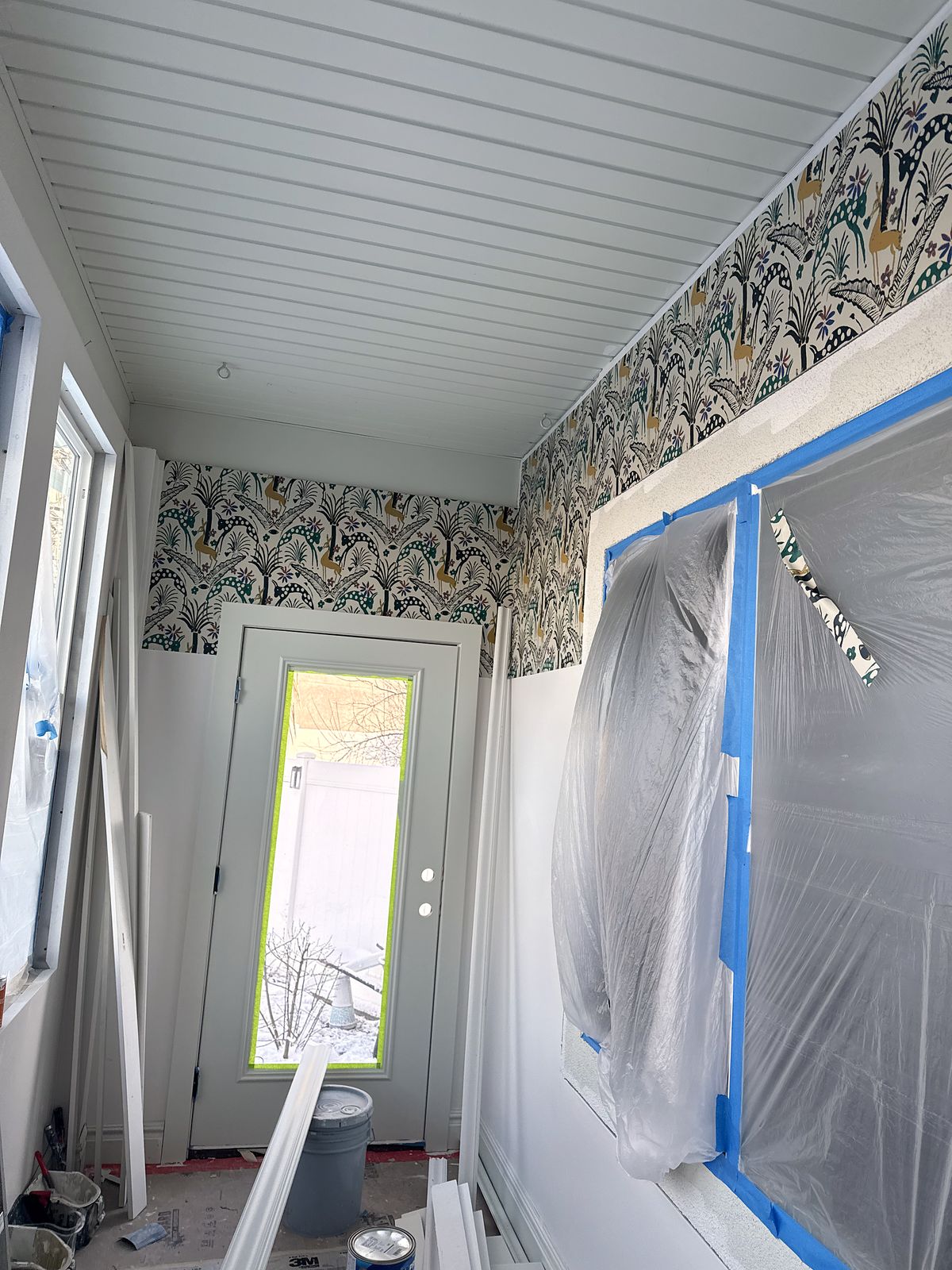 Botanical wallpaper going up above the new wainscoting, windows still masked