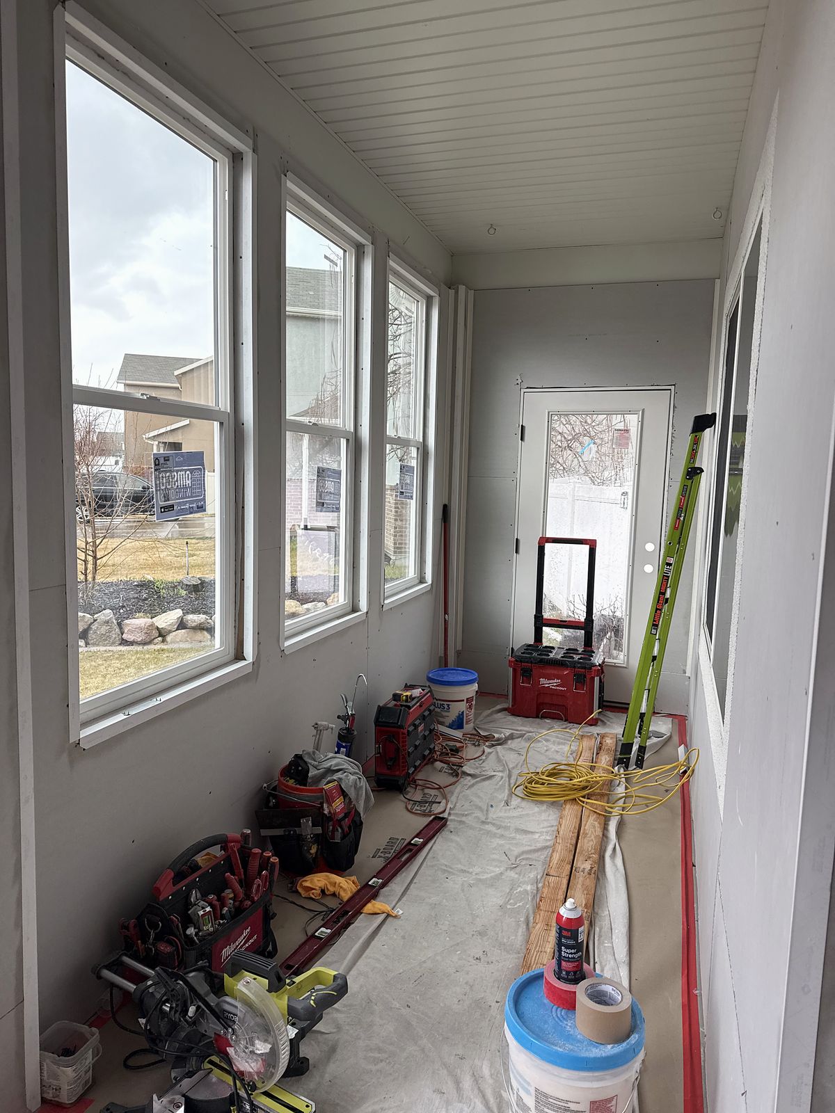 Mudroom interior with new walls, a run of windows and a planked ceiling, tools on the floor