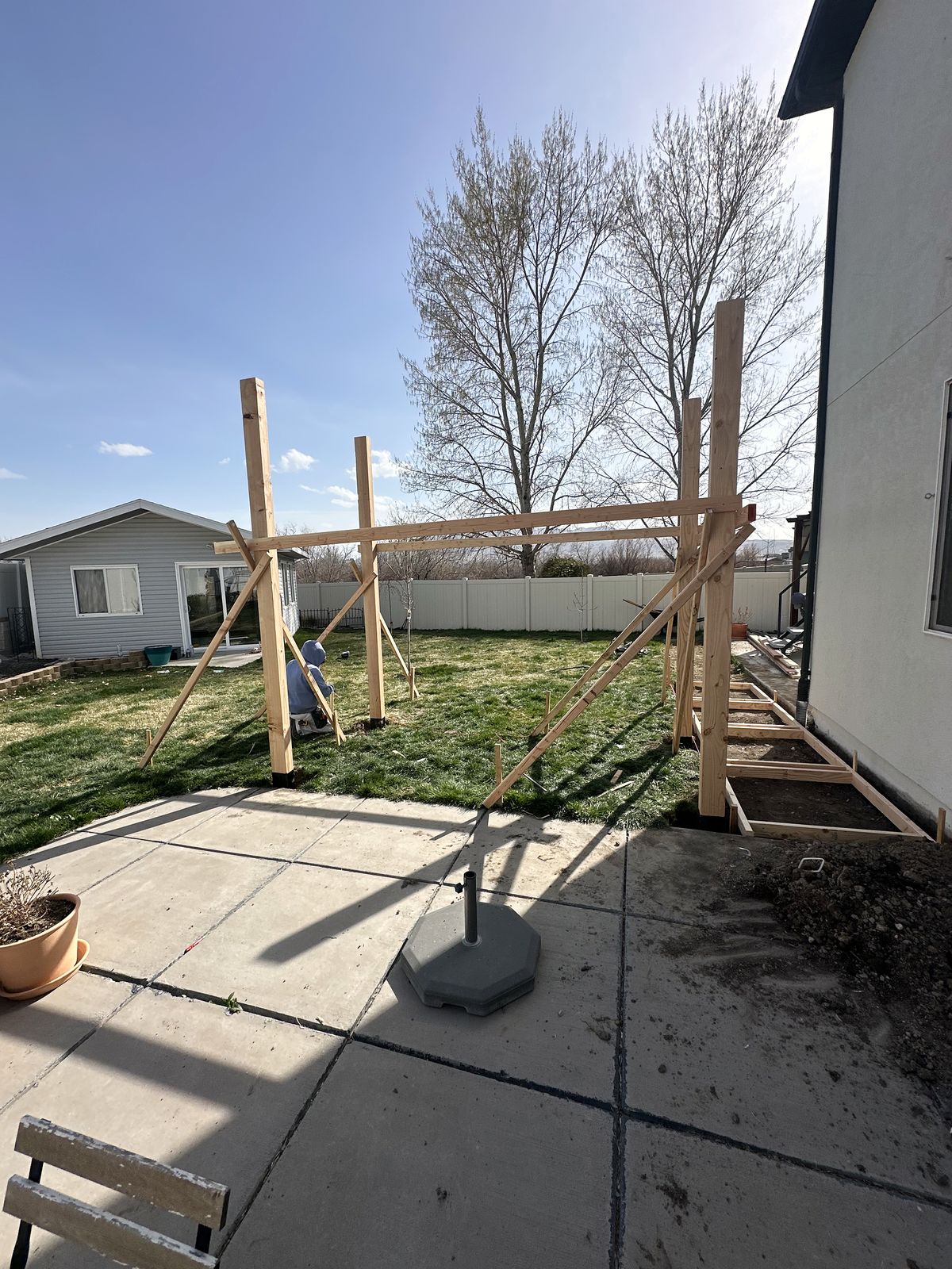 Pergola posts set and braced at the edge of the patio